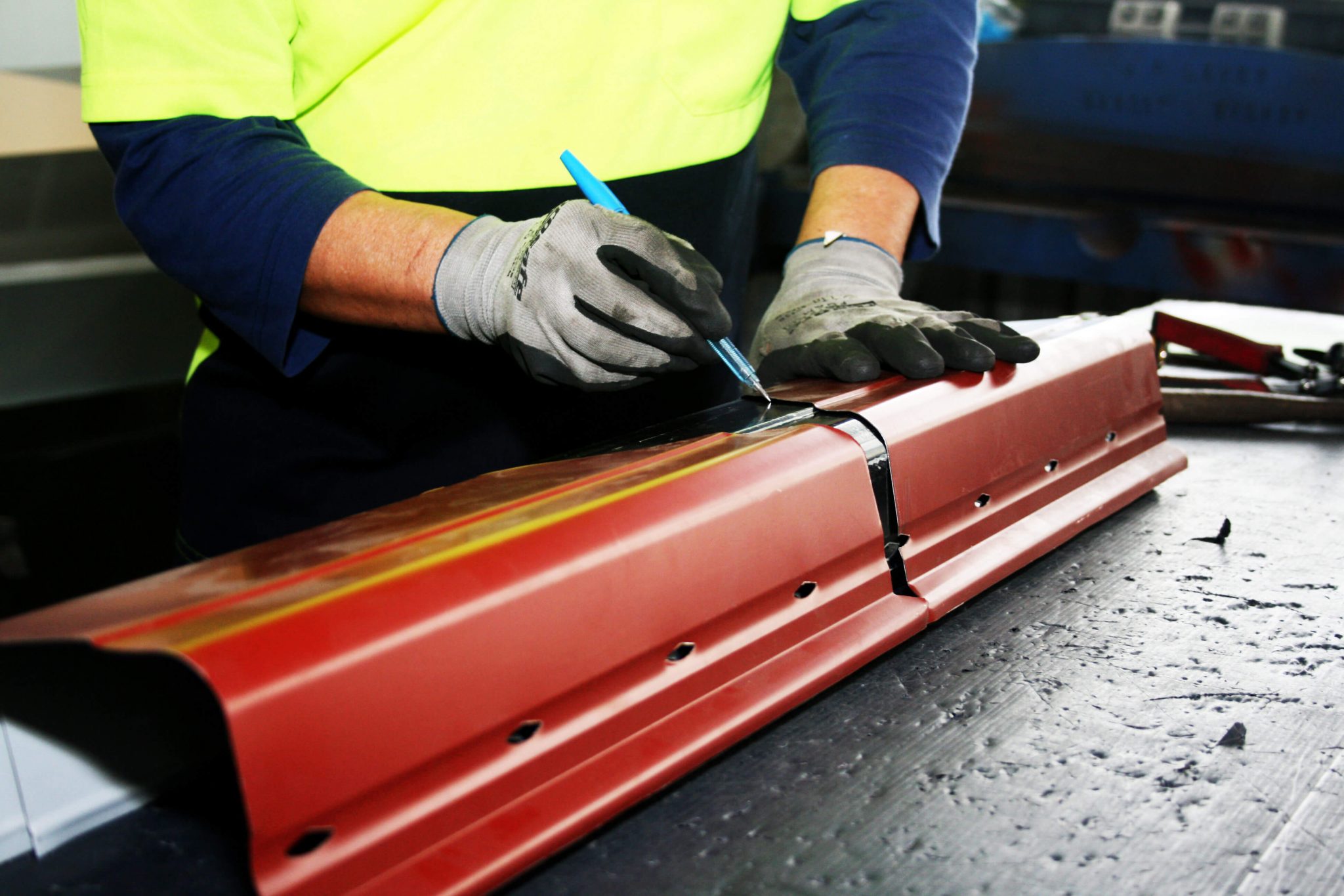 Professional worker working on red metal gutter at Queensland sheet metal workshop