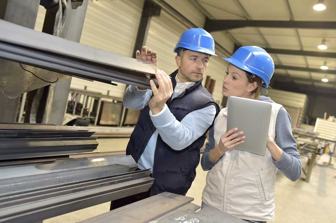 Two individuals wearing hard hats examining a tablet device.