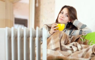 woman with yellow cup near oil heater at home