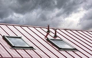 new grey metal roof with skylights against cloudy sky