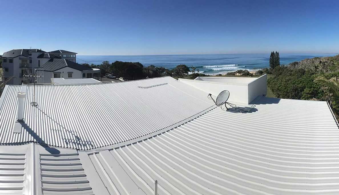 White metal roof overlooking ocean, clear blue skies.